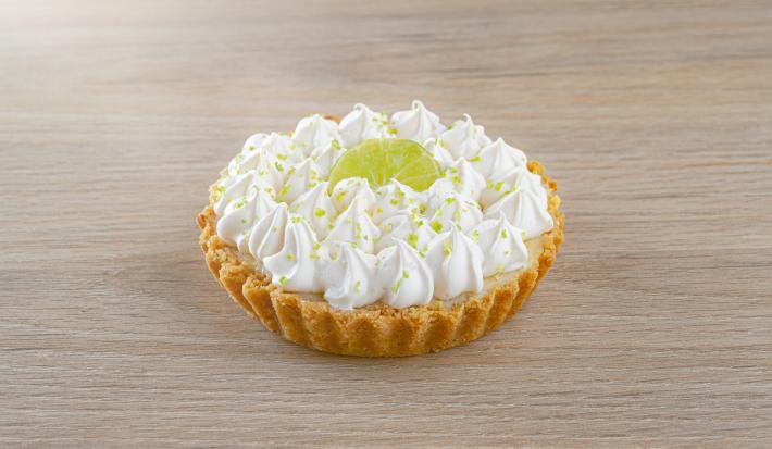 Fotografia de uma torta de limão pequena em cima de uma mesa de madeira.