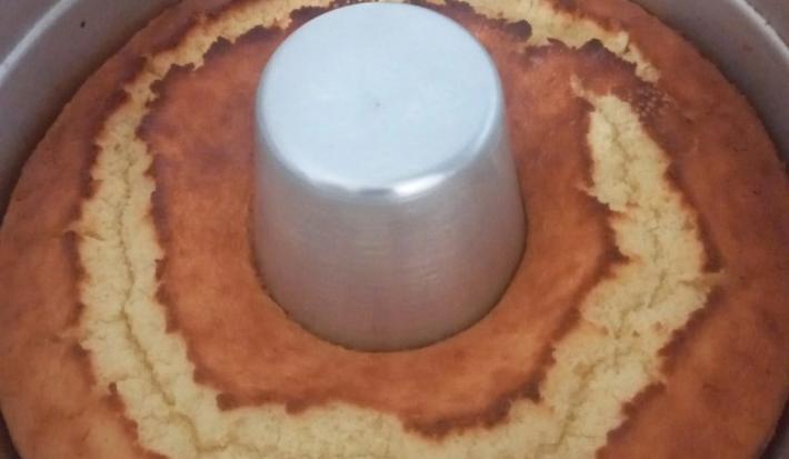 Foto da receita de Bolo de Arroz Cru. Observa-se um bolo assado ainda dentro de uma forma com furo no meio