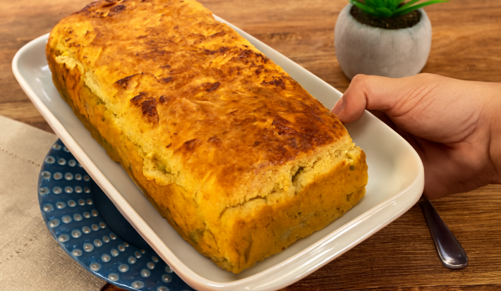Fotografia em tons claros com um prato retangular branco ao centro. Em cima do prato existe uma receita de pão de forma caseiro sem farinha feito com batata doce e NINHO Adulto
