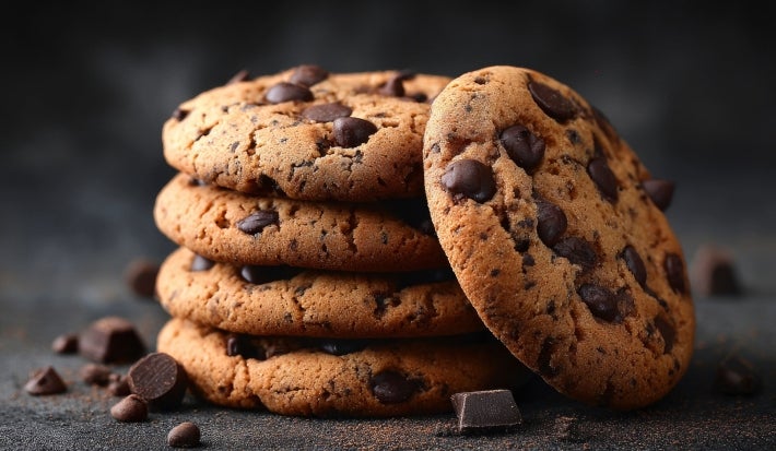 Em cima de uma mesa, biscoitos redondos crocantes com chocolate picado.