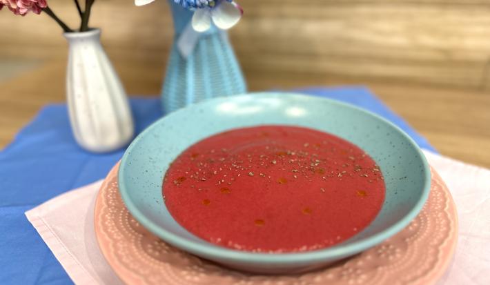 Fotografia em tons de rosa e azul com um prato azul ao centro. Dentro do prato existe uma receita de sopa de legumes com ASCENDA