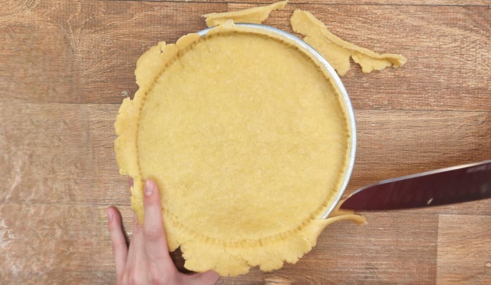 Faca cortando a massa excedente da torta selada.