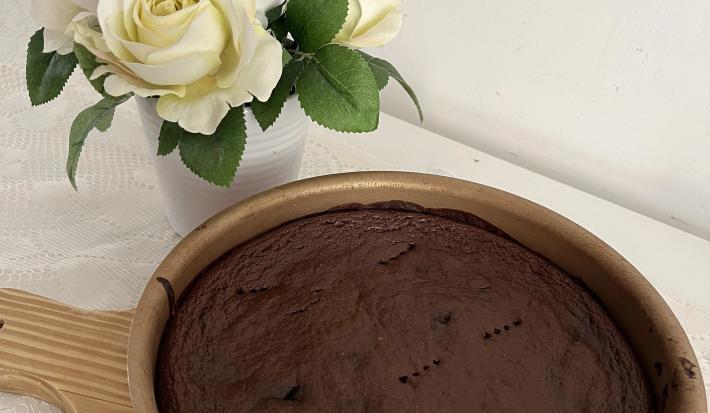 Fotografia de uma forma redonda antianderente com um brownie de chocolate e batata doce. A forma está sobre uma tábua de madeira.
