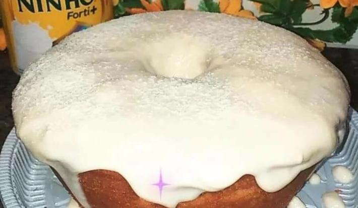 Foto da receita de Bolo de Ninho. Observa-se um bolo assado com furo no meio e bastante cobertura polvilhada de Leite Ninho