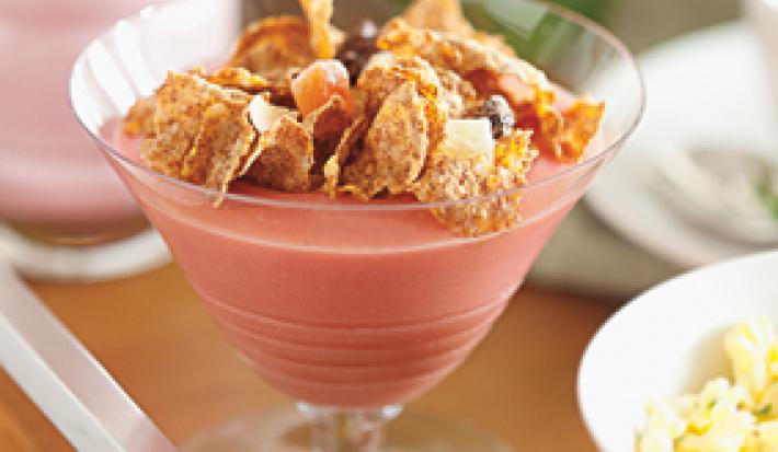 uma taça transparente contém creme de goiaba com cereal por cima