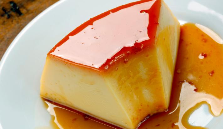 foto da receita de pudim de leite condensado tradicional, receita do consumidor, servido em um pedaço sobre um prato branco com calda de caramelo escorrendo
