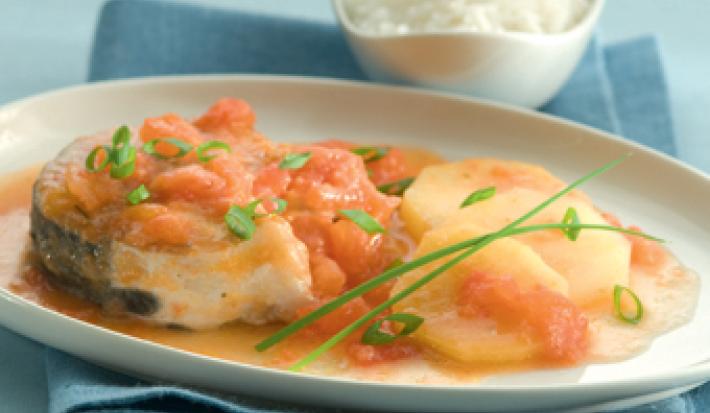 Fotografia em tons de azul e laranja, ao centro um pano azul e acima dele um prato branco com pedaços de peixe e ao lado um potinho com arroz.