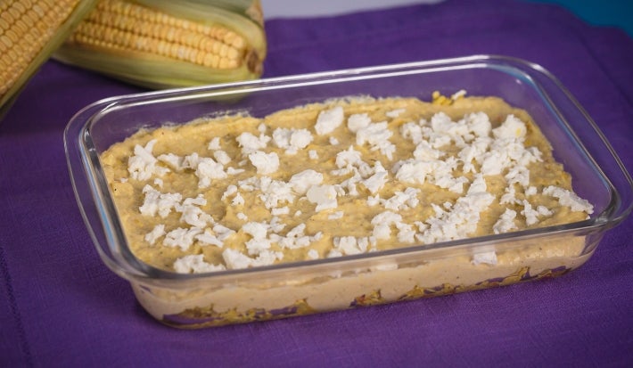 Fotografia em tons amarelo e roxo com uma travessa de vidro ao centro. Na travessa, existe uma receita de Fricassê de frango feita com Ascenda e finalizada com queijo branco.