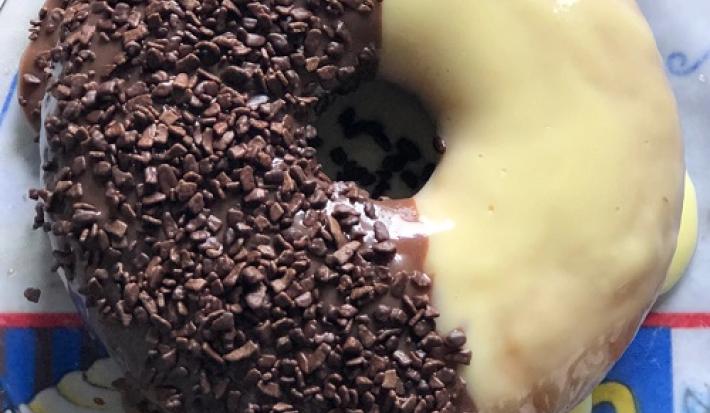 Foto da receita de Bolo Dois Amores. Observa-se um bolo visto de cima metade com branco e metade preto. A parte branca tem uma cobertura e a parte preta está coberta por granulado.