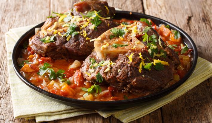 Foto da receita de Chambari. Observa-se um prato fundo com a carne cozida com bastante molho dentro, sobre uma superfície de madeira.