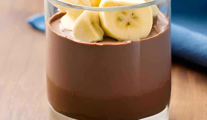 Foto da Receita de Mousse Chocolate com Banana. Observa-se um copo com o mousse dentro e bananas decorando o topo. Imagem ilustrativa gerada por inteligência artificial.