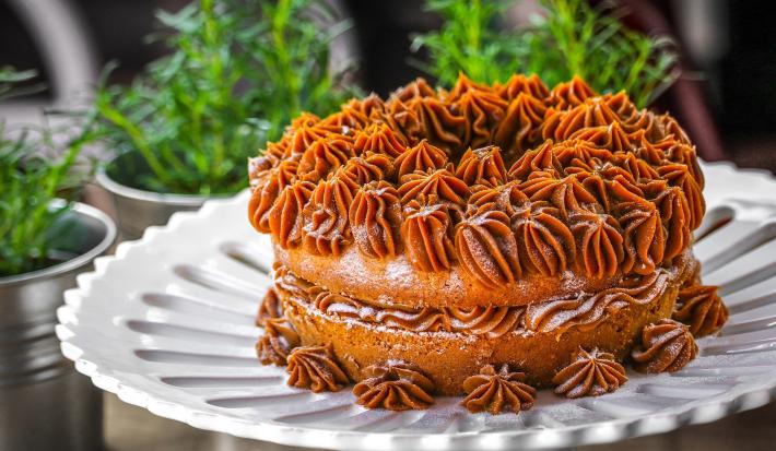 Imagem de um prato branco com um bolo de churros decorado com doce de leite feito com bico de confeitar.