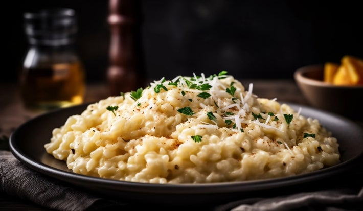 imagem mostra um prato com risoto em tons claros, pedaços de palmito e salsinha polvilhada por cima.