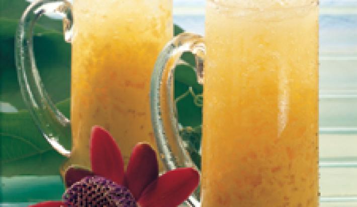 fotografia tirada de dois copos transparentes com o refresco de maracujá com gelo picado por cima