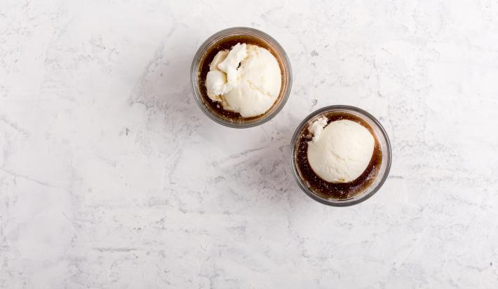Fotografia vista de cima de dois recipientes pequenos de vidro com affogato delicioso feito com Prestígio Morango, sorvete de creme e NESCAFÉ. Os recipientes estão sobre uma mesa de mármore branca.