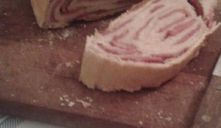 Foto da receita de pão de linguiça tartano servida em duas porções grandes cortadas ao meio sobre uma tábua de madeira