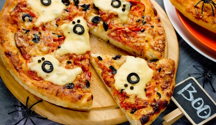 Pizza com massa dourada, fantasmas de queijo, olhos de azeitona preta e borda crocante, pronta para servir no Halloween.