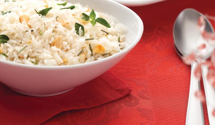 fotografia em tons de vermelho e branco, contém um pano vermelho e por cima um recipiente redondo branco com arroz e ao lado colheres para servir