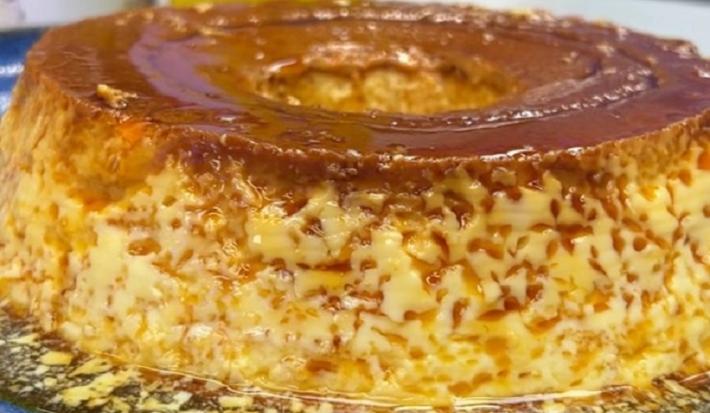 Foto da receita de pudim de leite moça na panela servida em uma porção grande sobre uma bancada cinza