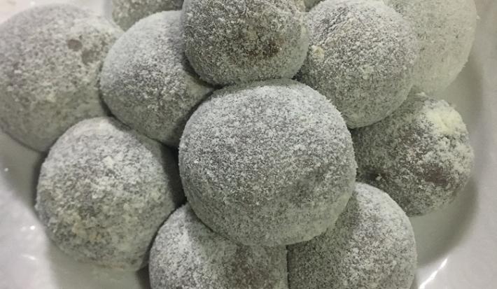 Foto da receita de Brigadeiro Proteico. Observa-se vários brigadeiros boleados e polvilhados sobre um prato branco.