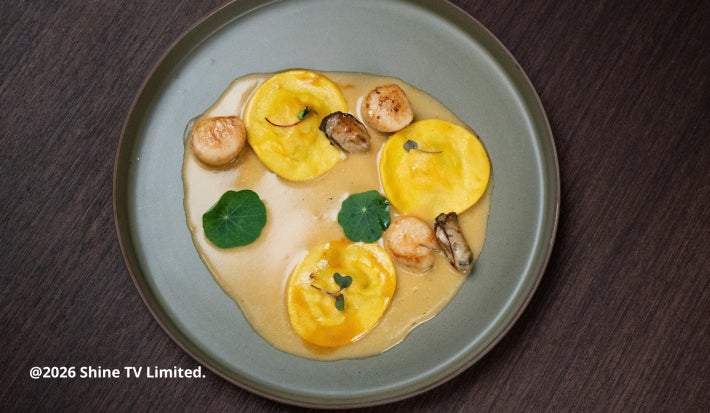 Tortelloni de camarão com molho bisque, vieiras grelhadas e flores de capuchinha em prato sofisticado e cheio de sabor.