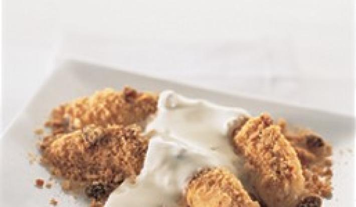 fotografia em tons de branco e marrom tirada de uma prato branco retangular com duas bananas assadas com creme de leite por cima