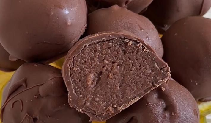 Fotografia em tons de amarelo com um prato amarelo ao centro. Em cima do prato existe uma receita de trufas de chocolate com laranja cobertas com chocolate ao leite