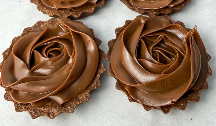 Fotografia em tons claros de algumas tarteletes de brigadeiro com massa de chocolate ao centro