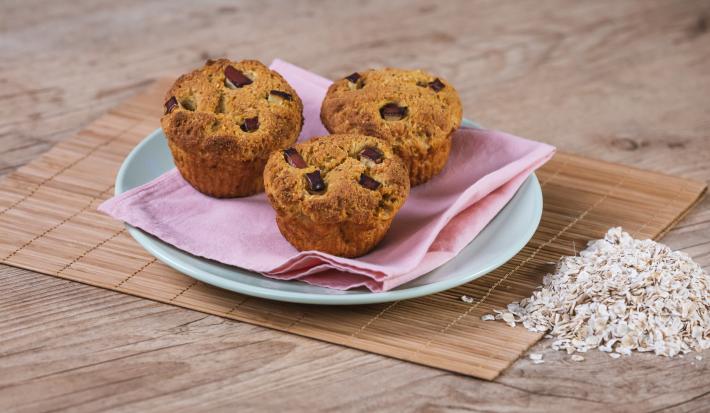 Foto da receita de Muffin de Maçã e Manga. Observa-se 3 muffins em cima de um guardanapo rosa e um prato azul.