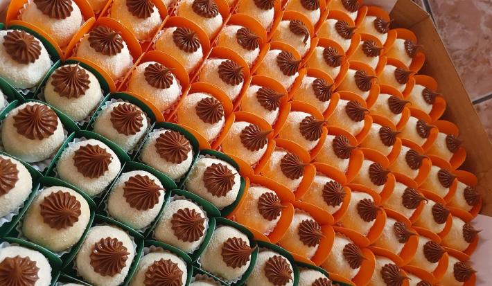 Foto da receita de Brigadeiro com Creme de Avelã. Observa-se inúmeros brigadeiros em forminhas dispostos em uma caixa decorados com creme de avelã em cima, feito com bico de confeiteiro