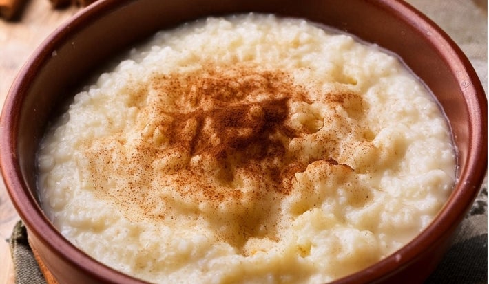 Tigela redonda de porcelana marrom com arroz cremoso com canela em pó.