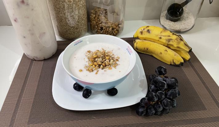 Imagem da receita de Iogurte Caseiro de Morango em um bowl, sobre uma mesa com bananas e uvas ao lado