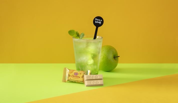 Foto da receita de Soda Italiana Apple Green. Observa-se um fundo amarelado e verde com um copo alto no centro, decorado com folha de hortelã. Uma maçã verde atrás do copo decora a foto.