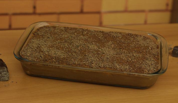 Fotografia em tons de marrom de uma bancada marrom com um recipiente refratário com o pavê. Fotografia em tons de marrom de uma bancada marrom com um recipiente refratário com o pavê.