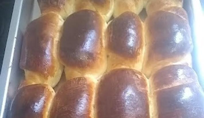 Foto da receita de Pão Sem Lactose. Observa-se um recipiente refratário preenchido de pães assados e dourados.