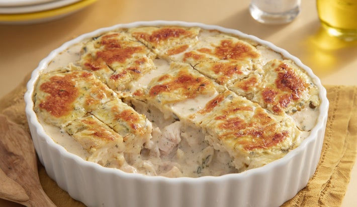 Caçarola cremosa assada com frango e molho branco, gratinada com superfície dourada, servida em refratário branco.