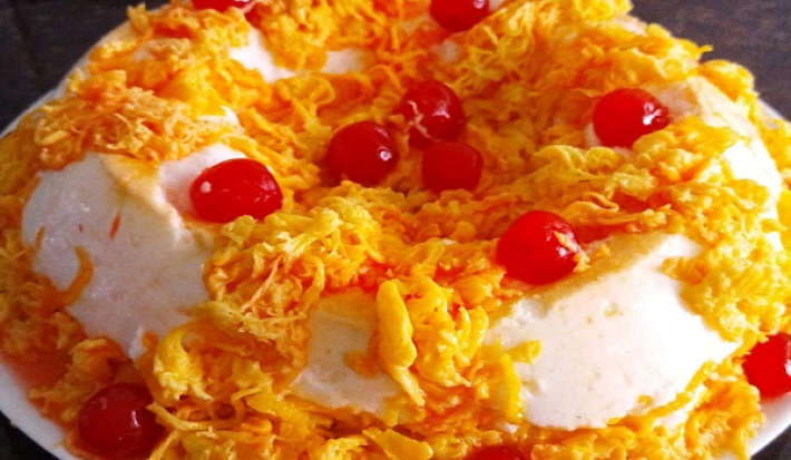 Foto em tons de amarelo da receita de pudim de clara de panetone com fio de ovos com cerejas por cima para decorar