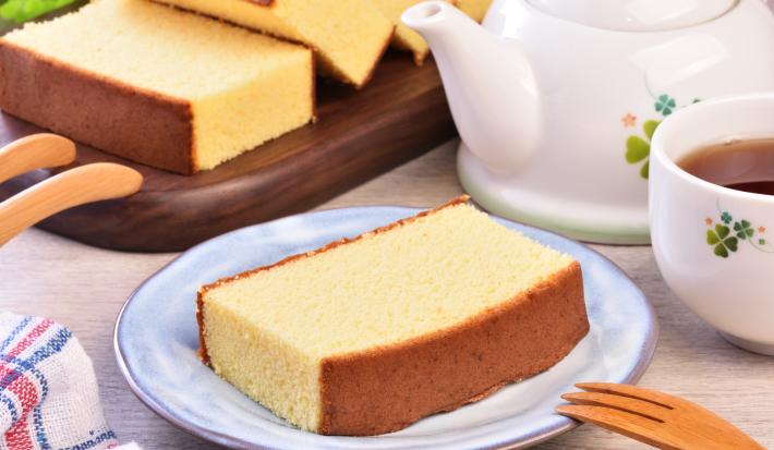 Foto da receita de Bolo Japonês. Observa-se uma fatia de bolo servida em um prato de cerâmica e, ao lado, uma xícara de chá.