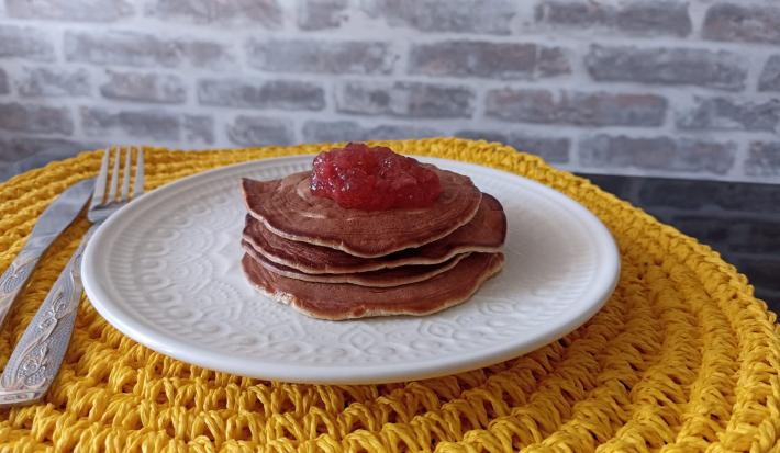 Imagem Imagem da receita de Panqueca Americana nutritiva com cobertura de geleia de frutas, em um prato branco, e ao lado os talheres