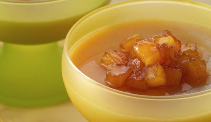Fotografia em tons de amarelo em uma mesa com uma toalha amarela, potinhos de acrílico amarelo com a sobremesa feita com abacaxi, canela e calda de abacaxi caramelizado.