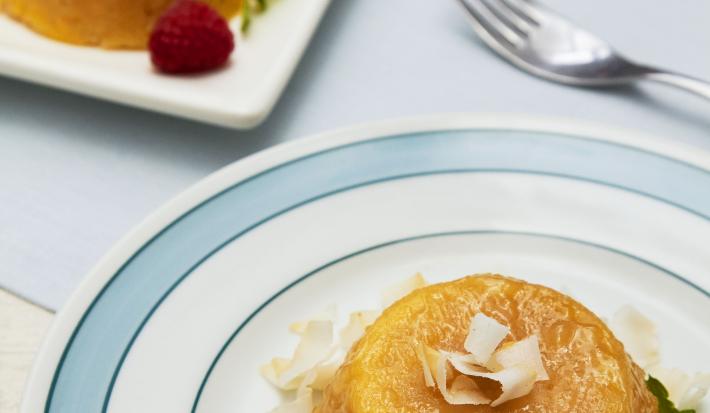 Foto de um prato azul com branco com um quindim dentro decorado com lascas de coco e morangos