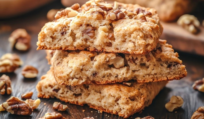 Em cima de uma mesa, pedaços de biscoitos de nozes picadas enfileirados em cima do outro.