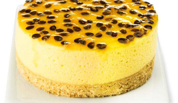Fotografia em tons de amarelo em uma bancada e fundo branco, um recipiente branco retangular e a torta de maracujá com requeijão em cima dele.