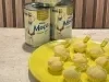 Docinhos cobertos com coco ralado em prato amarelo, com cápsulas decorativas e latas de Leite Moça ao fundo.