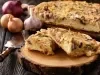 Fotografia de dois pedaços de torta recheada de cebolas sobre um apoio redondo de madeira. Ao fundo tem o restante da torta sobre um apoio de madeira.