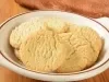 Em cima de uma mesa, prato redondo com biscoitos redondos crocantes e dourados.