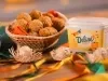 Bolinho de milho recheado com frango em cesta, milho e pote de margarina Deline ao lado