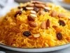 Prato redondo com porção de arroz soltinho com amêndoas e uvas-passas pretas.