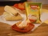 Sobremesa em cestinha crocante sobre prato vermelho, com embalagem Farinha Láctea Milho e espigas de milho ao fundo.