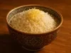 Em cima de uma mesa, tigela redonda branca com porção de arroz, decorado com raspas de limão.